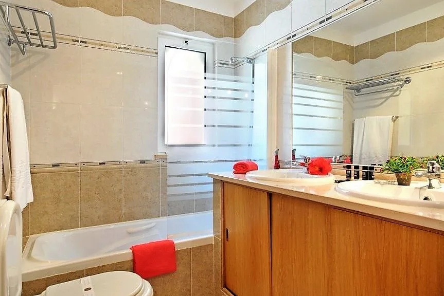 Bathroom with bathtub, mirrored vanity and wooden cabinetry at Jardim da Meia Praia, Lagos